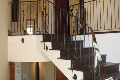 This is an example of a medium sized mediterranean wood curved metal railing staircase in Phoenix with wood risers.