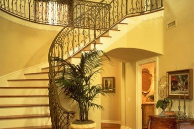 Staircase - large mediterranean wooden curved metal railing staircase idea in San Diego with painted risers
