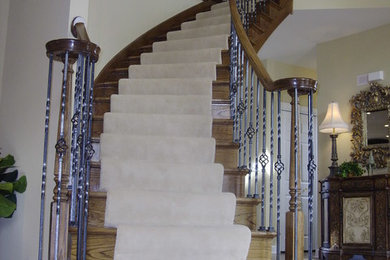Imagen de escalera curva con escalones de madera, contrahuellas de madera y barandilla de varios materiales