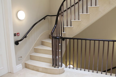 Réalisation d'un grand escalier carrelé courbe design avec des contremarches carrelées.