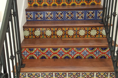 Foto de escalera recta mediterránea pequeña con escalones de madera, contrahuellas con baldosas y/o azulejos y barandilla de metal