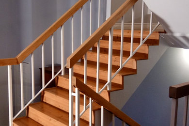 Imagen de escalera en U clásica de tamaño medio con escalones de madera, contrahuellas de madera y barandilla de madera