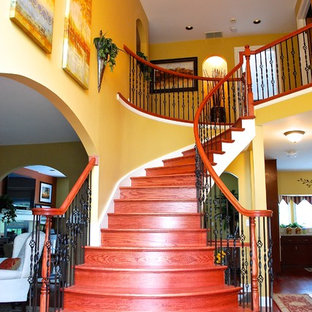 Réalisation d'un grand escalier courbe tradition avec des marches en bois et des contremarches en bois.
