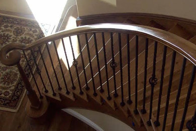 Ejemplo de escalera curva clásica de tamaño medio con escalones de madera y barandilla de metal