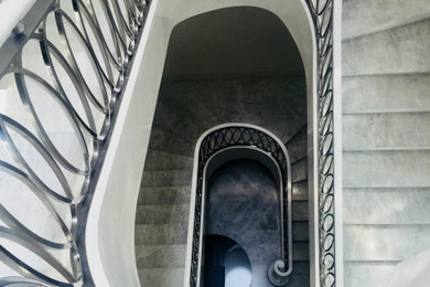 メルボルンにある高級な巨大なモダンスタイルのおしゃれなサーキュラー階段 (大理石の蹴込み板、金属の手すり、羽目板の壁) の写真