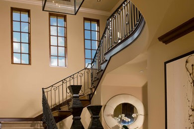 На фото: большая п-образная лестница в средиземноморском стиле с ступенями с ковровым покрытием, ковровыми подступенками и металлическими перилами с