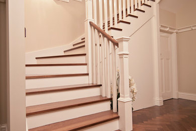 Diseño de escalera tradicional con escalones de madera, contrahuellas de madera pintada y barandilla de madera