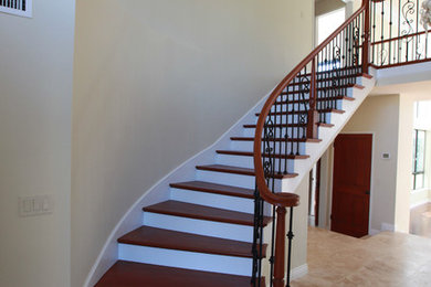 Photo of a large classic wood curved staircase in Los Angeles with wood risers.