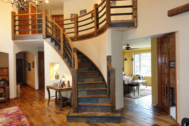 Foto de escalera curva rústica grande con escalones de madera, contrahuellas de pizarra y barandilla de madera