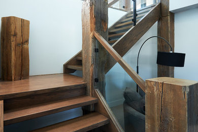 На фото: угловая лестница среднего размера в стиле модернизм с деревянными ступенями и стеклянными перилами
