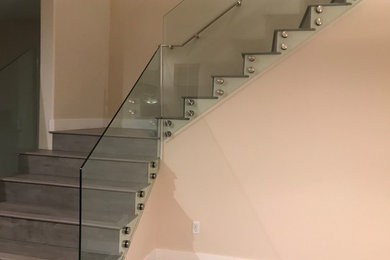 Example of a mid-sized minimalist wooden l-shaped glass railing staircase design in San Francisco with wooden risers