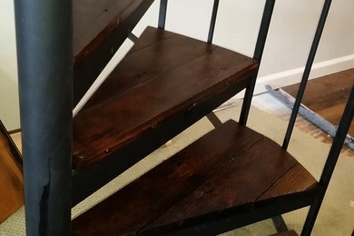 Ejemplo de escalera de caracol vintage de tamaño medio con escalones de madera y contrahuellas de metal