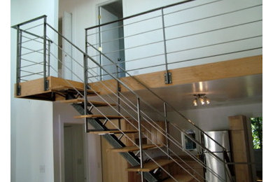 Exempel på en mellanstor modern l-trappa i trä, med sättsteg i trä och räcke i metall