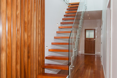Ejemplo de escalera suspendida contemporánea grande sin contrahuella con escalones de madera y barandilla de vidrio