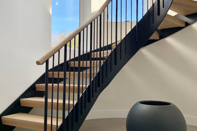 Inspiration for a large contemporary wooden curved open and metal railing staircase remodel in New York