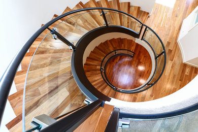 Foto på en mycket stor funkis flytande trappa i trä, med sättsteg i trä och räcke i glas