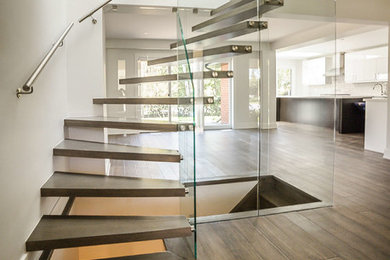 Imagen de escalera suspendida moderna de tamaño medio sin contrahuella con escalones de madera y barandilla de metal