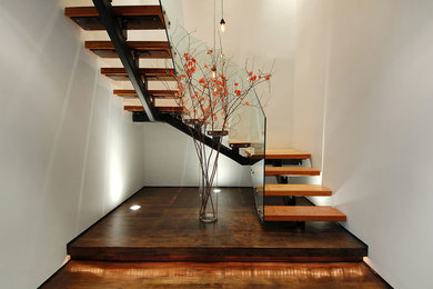 Large urban wooden u-shaped open and glass railing staircase photo in New York