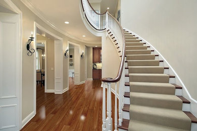 Large elegant carpeted curved wood railing staircase photo in Toronto with carpeted risers