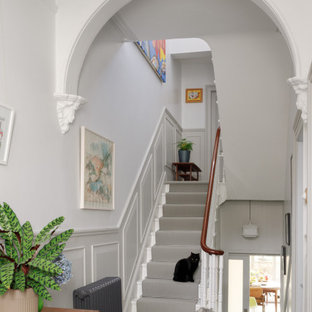 Diseño de escalera en U y boiserie, ecléctica, con escalones de madera pintada, contrahuellas de madera pintada, barandilla de madera y boiserie