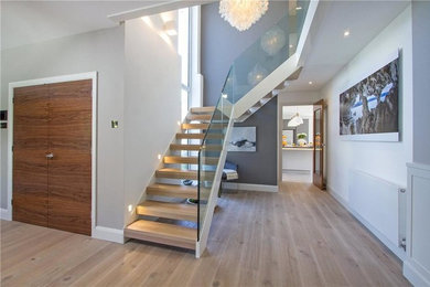 Large coastal wood l-shaped glass railing staircase in Sussex with open risers.