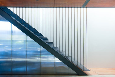 Imagen de escalera recta contemporánea sin contrahuella con escalones de metal y barandilla de cable