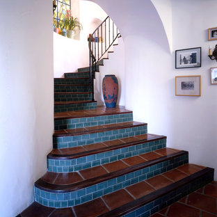 Ispirazione per una scala mediterranea con alzata piastrellata, pedata in terracotta e parapetto in metallo