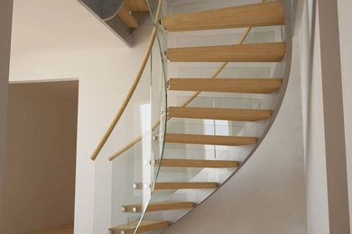 Medium sized contemporary wood curved staircase in Wiltshire with open risers.