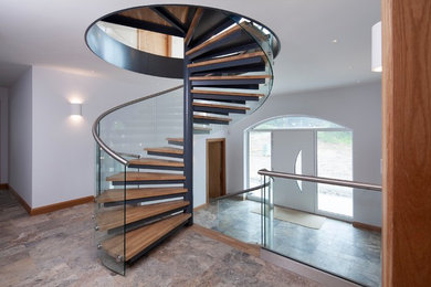 Large modern wood spiral mixed railing staircase in Cornwall with open risers.