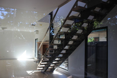 Diseño de escalera recta minimalista de tamaño medio con escalones de madera y barandilla de metal