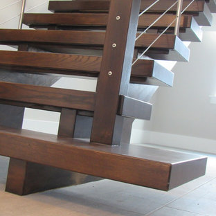 Foto di un'ampia scala sospesa contemporanea con pedata in legno, nessuna alzata e parapetto in cavi