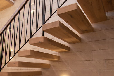 Ejemplo de escalera suspendida minimalista con escalones de madera y barandilla de varios materiales