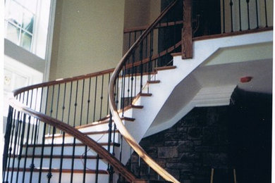 This is an example of a large modern wood curved staircase in Baltimore with wood risers.