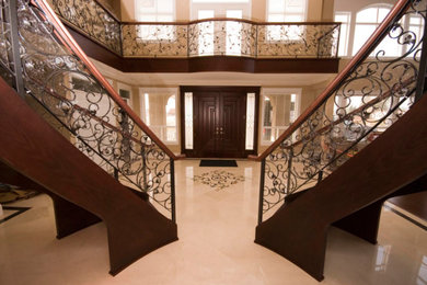 Идея дизайна: огромная изогнутая лестница в классическом стиле с перилами из смешанных материалов и деревянными ступенями без подступенок