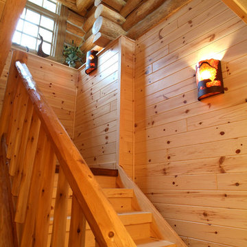 Staircase with cedar railing and knotty pine paneling