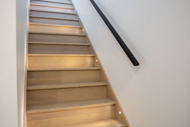 Diseño de escalera de caracol actual con escalones de madera, contrahuellas de madera y barandilla de vidrio