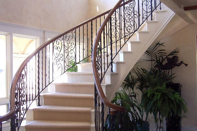 Modelo de escalera curva tradicional grande con escalones enmoquetados y contrahuellas con baldosas y/o azulejos