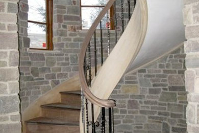 Exempel på en mellanstor klassisk svängd trappa i trä, med sättsteg i trä och räcke i metall