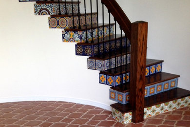 Ejemplo de escalera curva mediterránea de tamaño medio con escalones de madera y contrahuellas con baldosas y/o azulejos