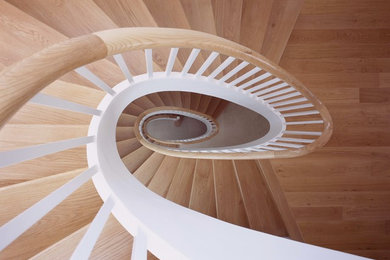Foto de escalera curva actual de tamaño medio con escalones de madera y contrahuellas de madera