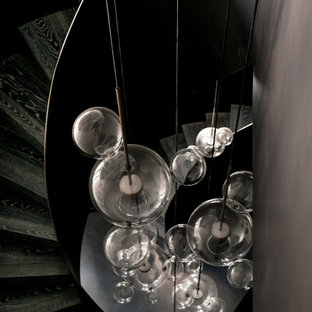 Esempio di una grande scala a chiocciola minimal con pedata in legno, alzata in metallo, parapetto in metallo e boiserie