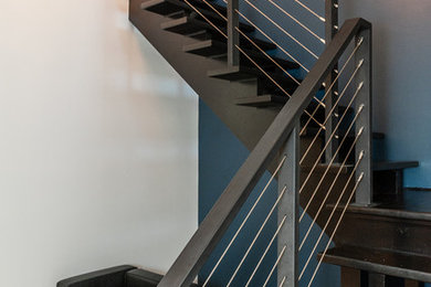 На фото: большая угловая металлическая лестница в стиле модернизм с металлическими ступенями и металлическими перилами с