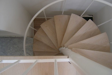 Foto de escalera de caracol sin contrahuella con escalones de madera y barandilla de metal