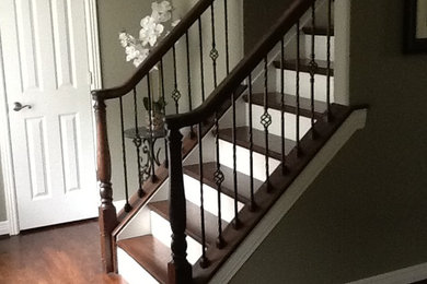 Diseño de escalera recta clásica de tamaño medio con escalones de madera, contrahuellas de madera pintada y barandilla de metal