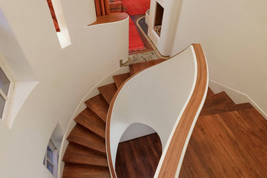 Imagen de escalera curva ecléctica de tamaño medio con escalones de madera, contrahuellas de madera y barandilla de madera