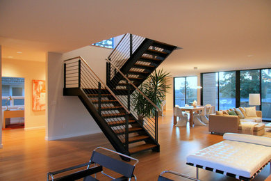 На фото: большая п-образная лестница в стиле модернизм с деревянными ступенями и перилами из смешанных материалов без подступенок