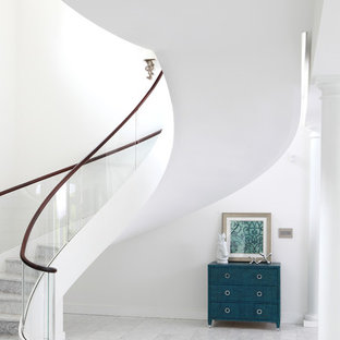 Aménagement d'un très grand escalier flottant contemporain avec des marches en marbre, des contremarches en marbre et un garde-corps en verre.