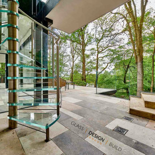 Imagen de escalera de caracol, contemporánea, con escalones de vidrio, contrahuellas con baldosas y/o azulejos y barandilla de metal