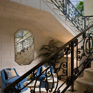 Immagine di una grande scala curva mediterranea con pedata in moquette, alzata in pietra calcarea e parapetto in materiali misti