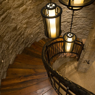 Immagine di una grande scala curva stile rurale con pedata in legno, alzata in legno e parapetto in metallo